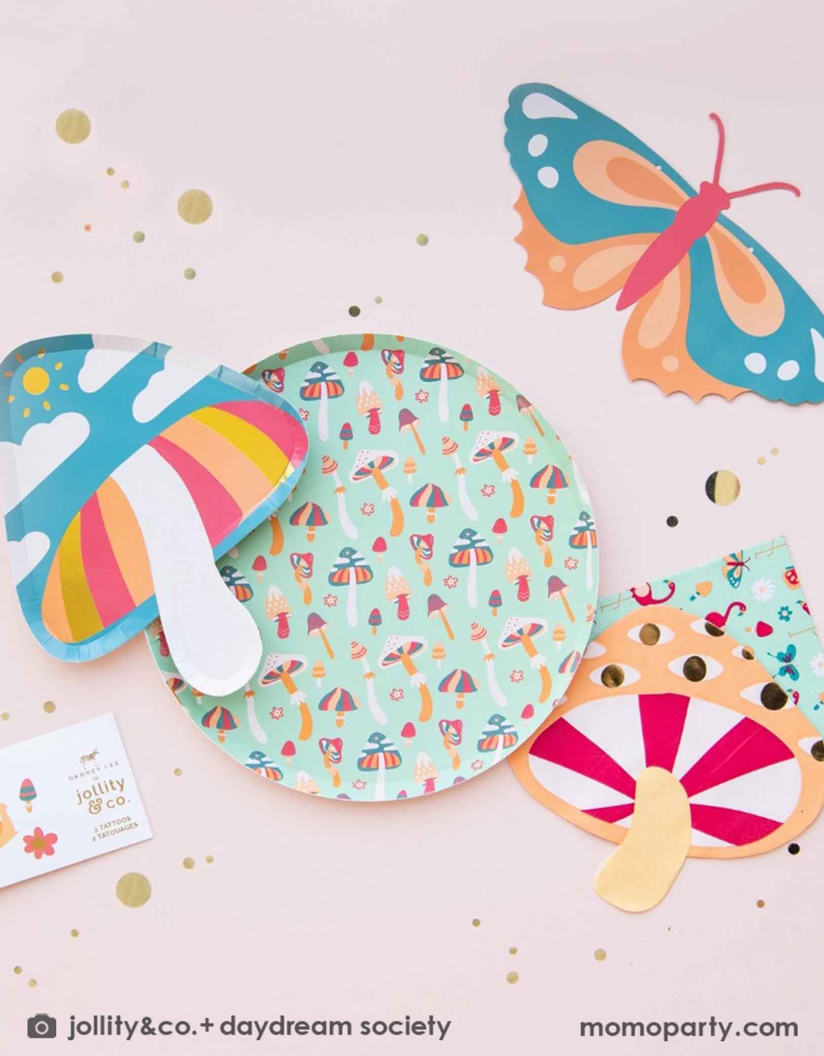 Momo Party's Alice Dreamland Whimsy Collection by Jollity & Co featuring colorful party plates, napkins, temporary tattoos and party pennants including mushrooms and a butterfly on a light pink background.