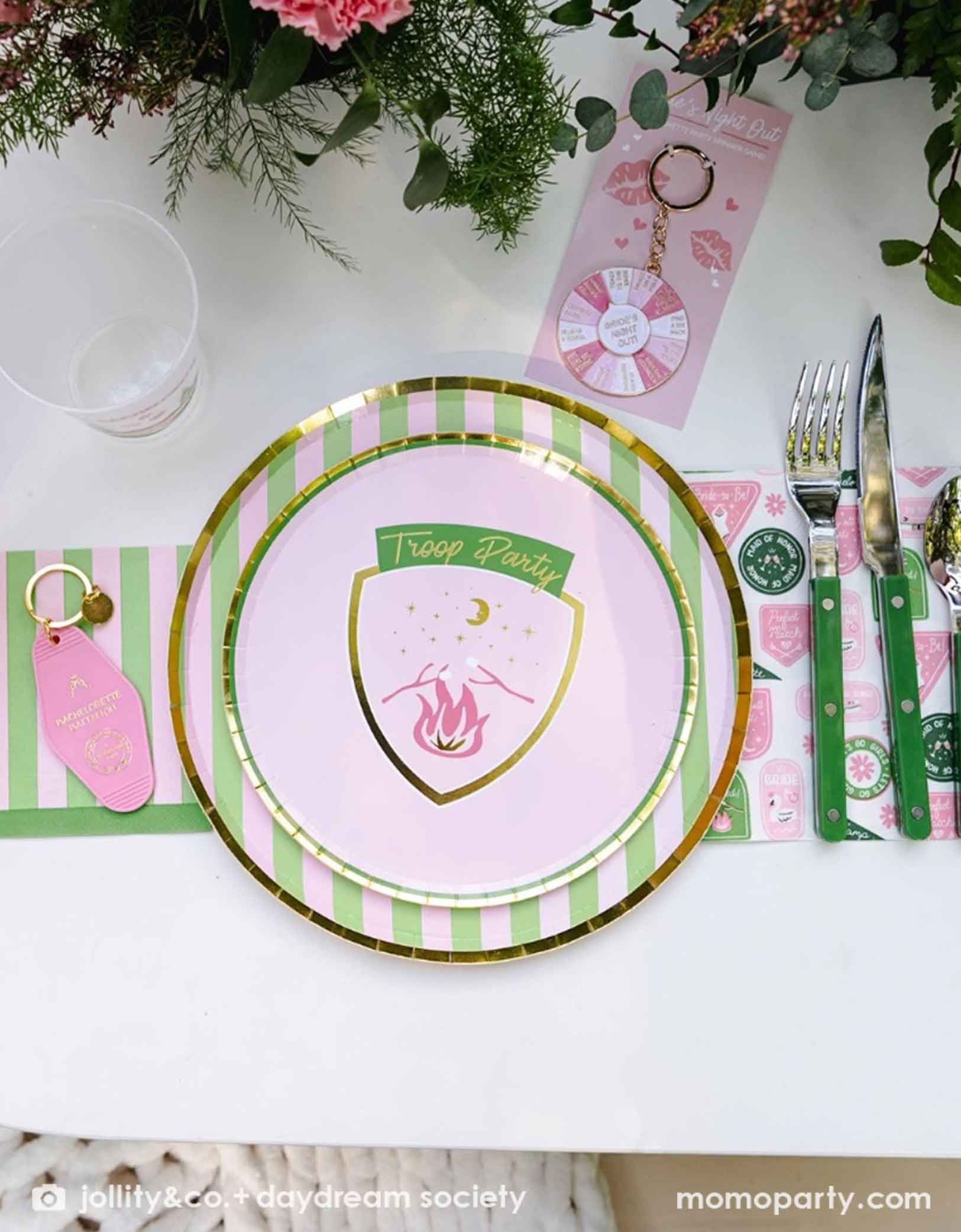 A beautiful bachelorette party table setting with Camp Bachelorette themed pink and green plates, napkins and cutlery from Momo Party.