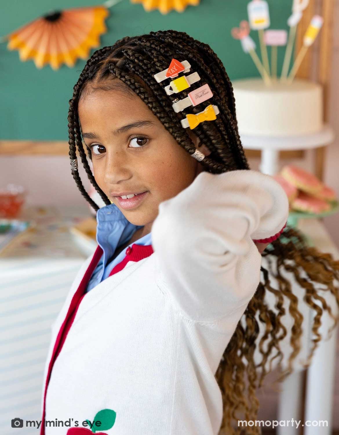 A young girl in her uniform with braided hair wearing Momo Party's colorful back to school hair hair clips in a classroom setting.