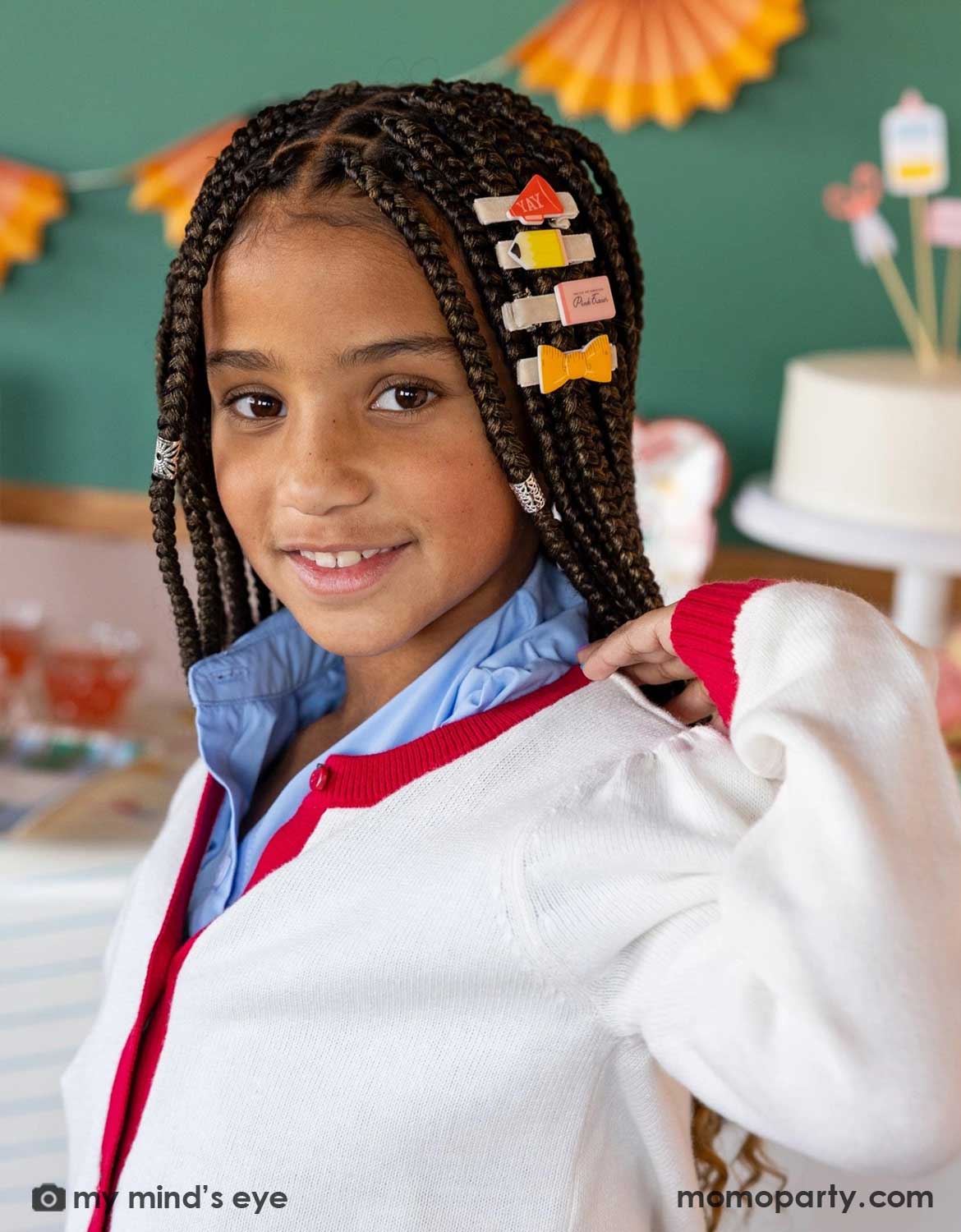A young girl in her uniform with braided hair wearing Momo Party's colorful back to school hair hair clips in a classroom setting.