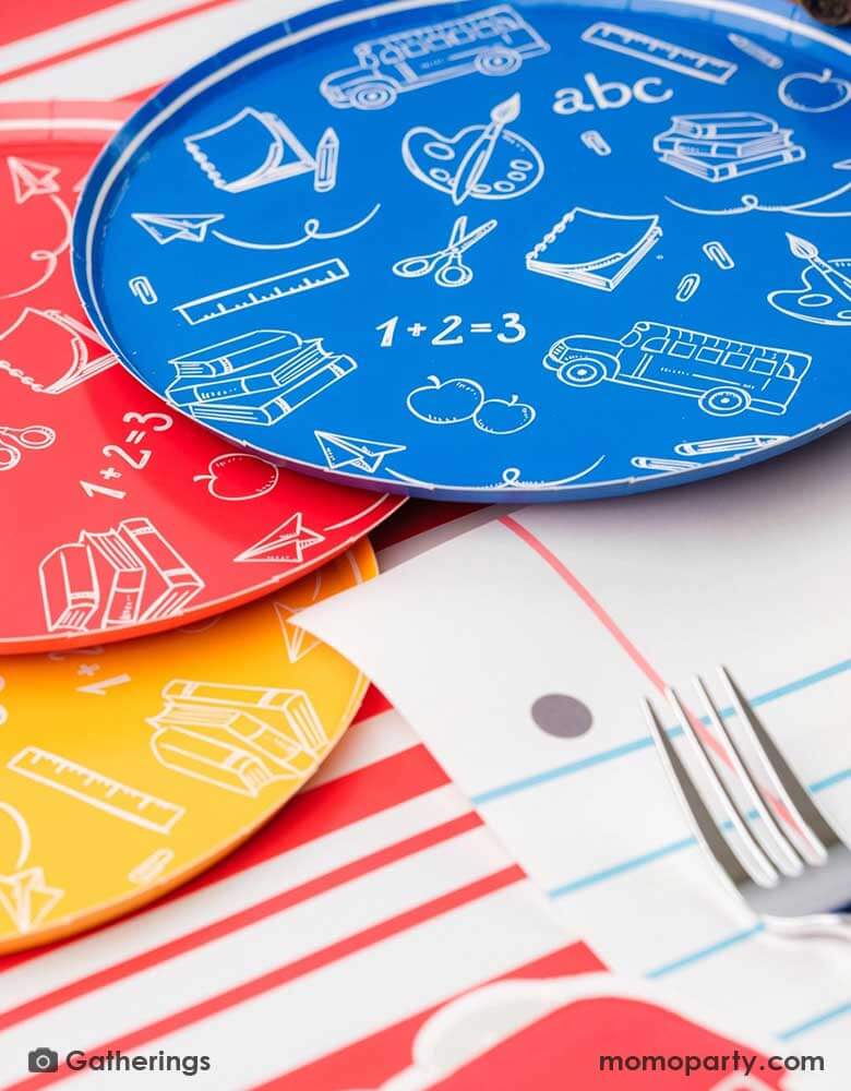 A close up of a back to school party featuring school themed party supplies from Momo Party including school day assorted side plates with school supply patterns in 4 colors of green, blue, red and yellow, with the No. 2 pencil patterned dinner plates and loose leaf paper placemats by Gatherings. A perfect place setting to celebration kid's or student's first day of schoo,