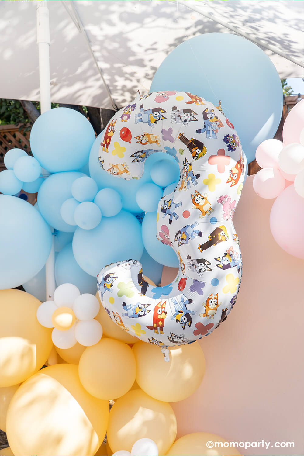 Momo Party's 26" Bluey themed number three foil balloon along with Bluey themed balloon garland in pastel peach, pink and blue adorned with daisy balloons. Featuring bright colors and fun Bluey and Bingo designs, this number 3 foil balloon adds a playful touch to any kid’s birthday party. Its large size makes it a standout decoration, perfect for capturing joyful memories and brightening up the celebration space. This adorable setting is perfect for your Bluey-loving child's birthday celebration.