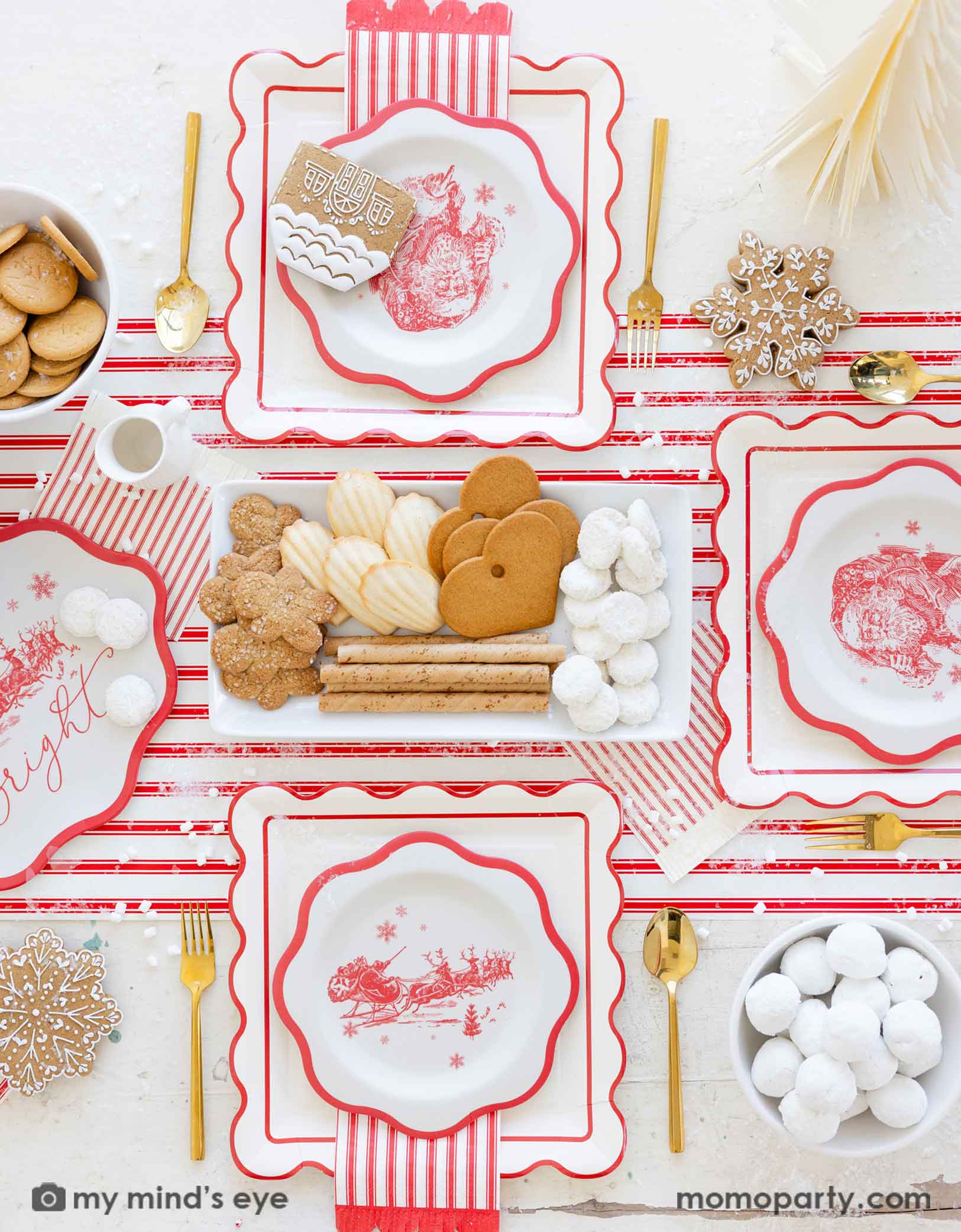 Christmas-themed table setting with red and white plates with Santa design, red striped napkins, cookies, and gold utensils on a matching red striped table runner from Momo Party.
