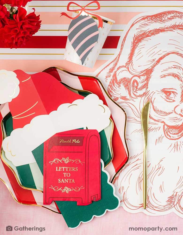 A festive Christmas party tablescape featuring Momo Party's Holiday red striped dinner plates and green side plates, along with a Santa hat shaped place card and a letter to Santa mail box shaped napkin, all on a Santa face placemat on a red and pink striped table runner. With ornament party cups and red floral arrangement, this makes a jolly table setting for this Holiday season.