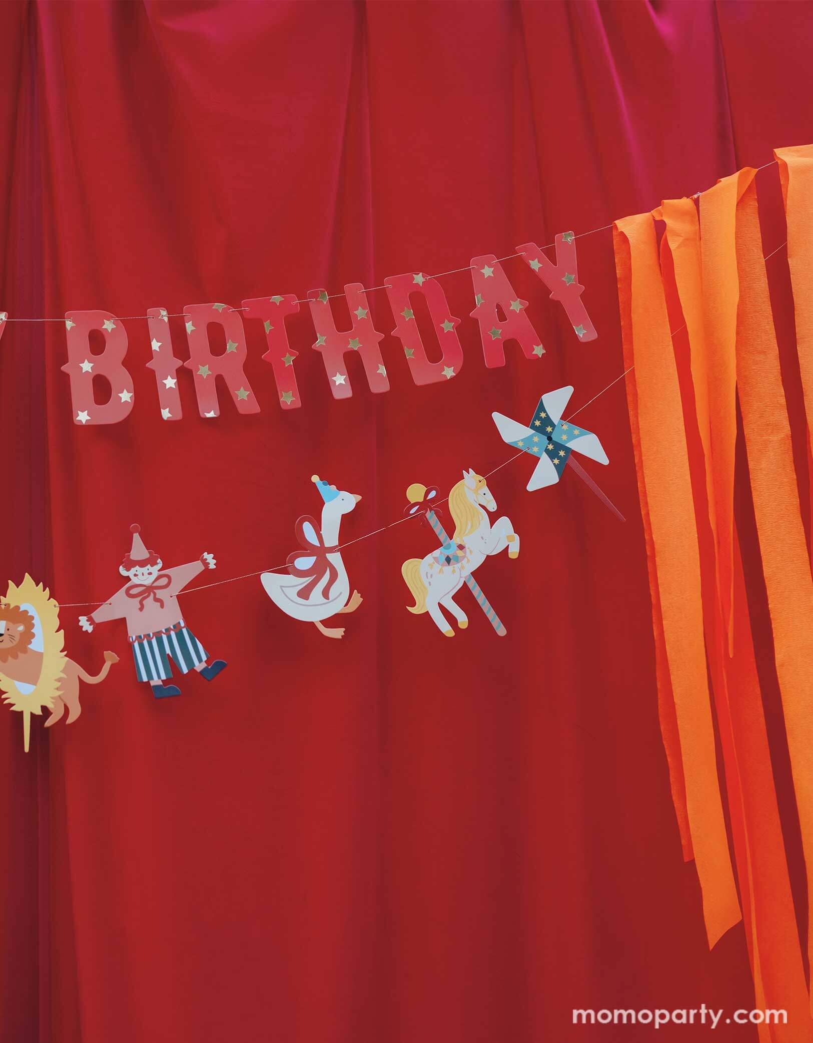 A vintage circus themed party backdrop with a red stage curtain decorated with Happy Birthday circus banner from Momo Party. Featuring fun and festive circus animals, bright orange streamers, and the classic "Happy Birthday" message, this banner will add a playful touch to any party. Bring the carnival to your birthday bash with this fun and colorful set!
