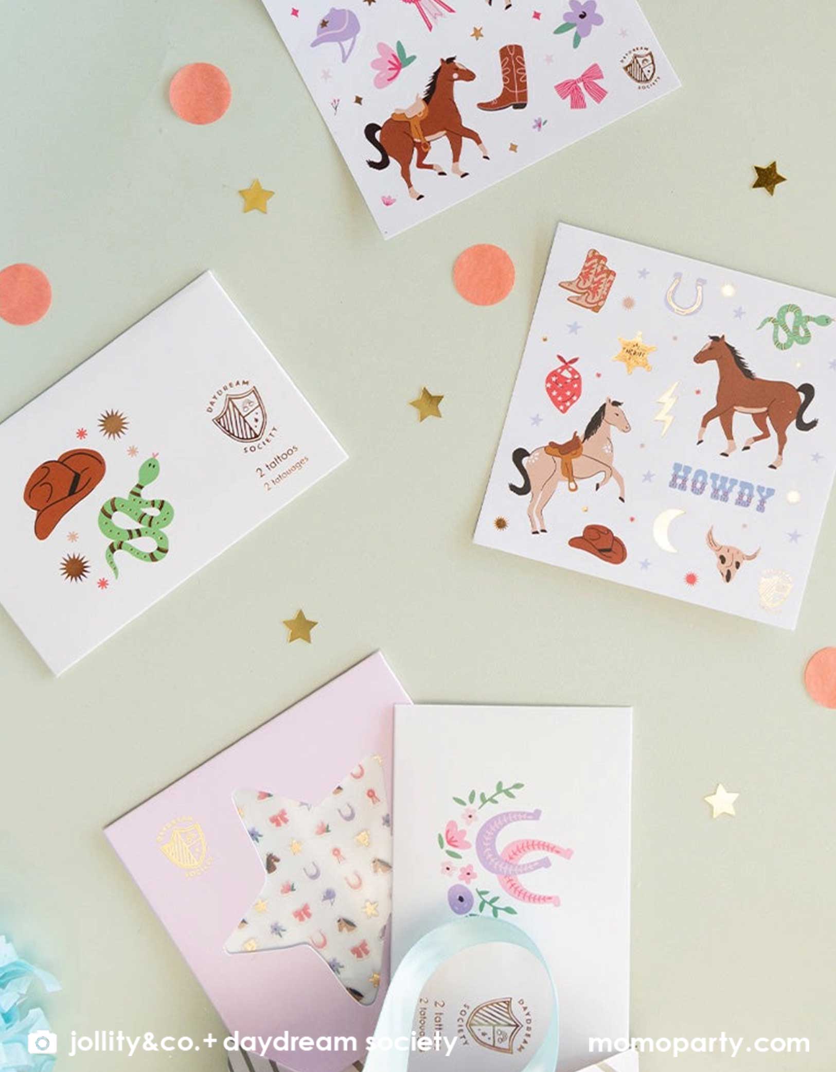 An overhead shot of Momo Party's Pony Tales Sticker Set, temporary tattoo sheets and Yeehaw cowboy temporary tattoos by Daydream Society. These temporary tattoo and stickers include images of horses, ribbons, florals and bows, cowboy hat, cowboy boots, horseshoes and snakes! They make the perfect birthday party favor or gift for a Western themed party or a horse/pony themed birthday bash!