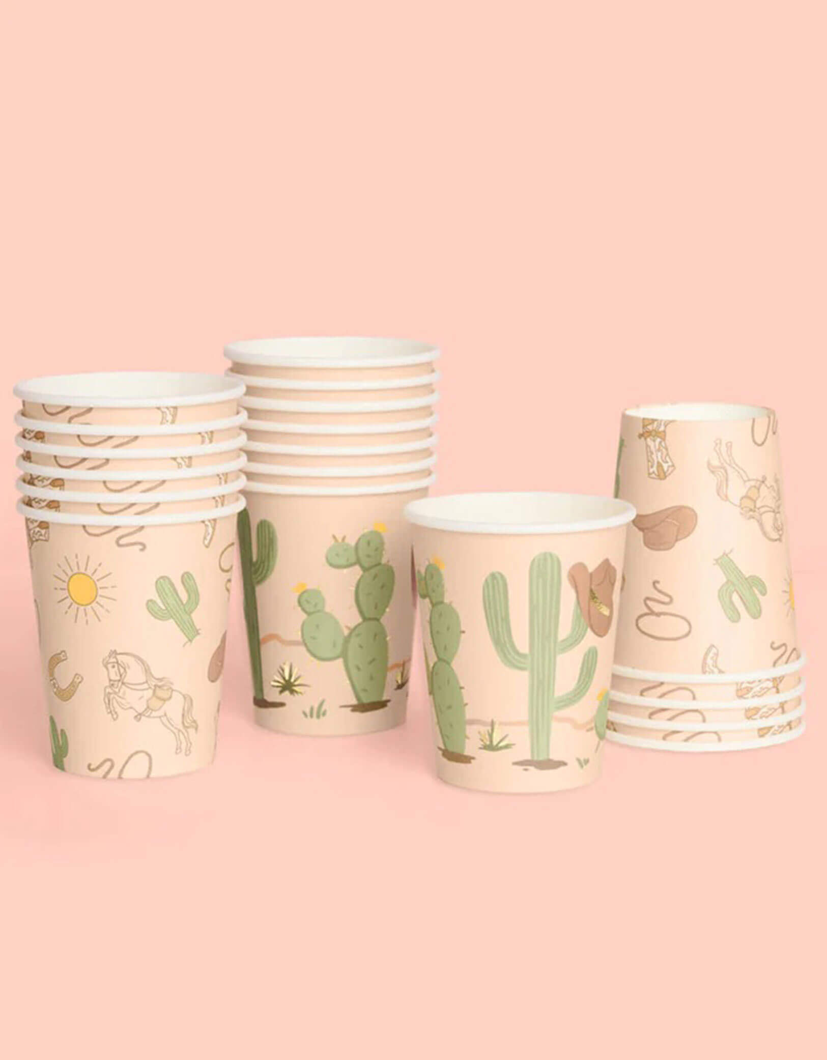 A set of Momo Party's Wild Wild West Party Cups with Western desert-themed designs including cactus, cowboy hat, horseshoe and cowboy boots on a pink background.