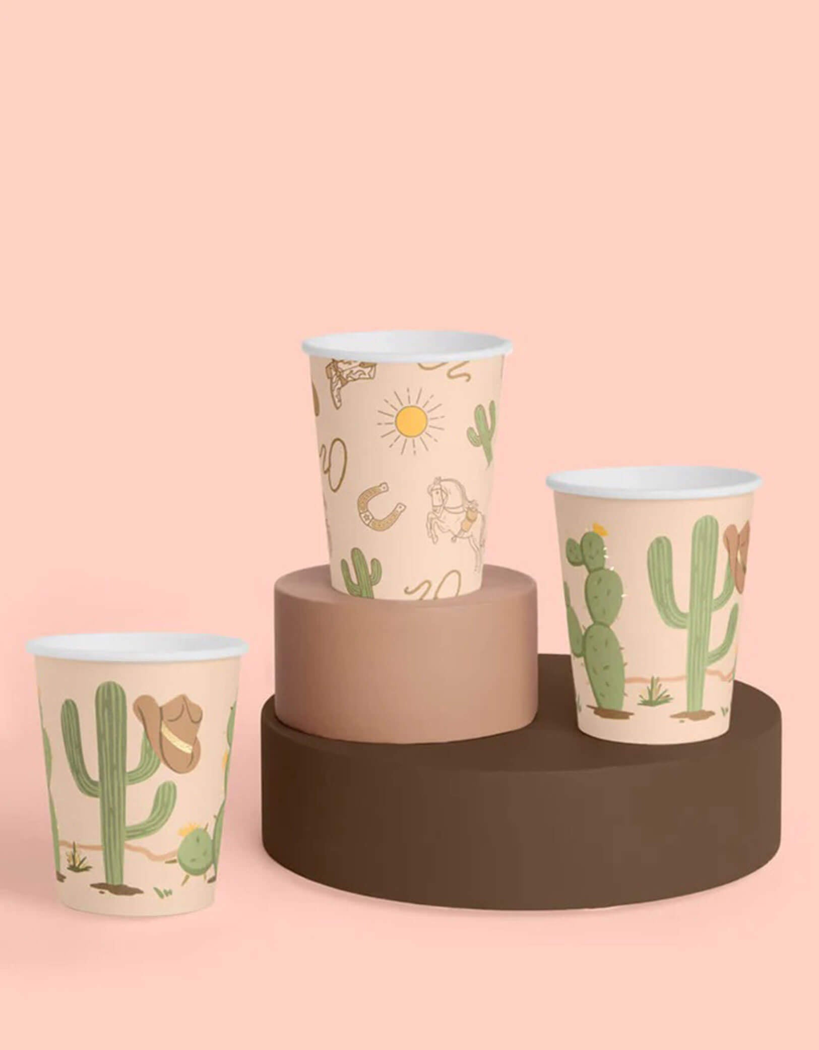 Three Momo Party's Wild Wild West Party Cups with Western desert-themed designs including cactus, cowboy hat, horseshoe and cowboy boots on a pink and brown background.