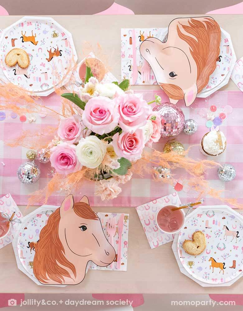 A cowgirl pony themed birthday party table featuring Momo Party's 9" x 11" pony shaped plates, cowgirl motif side plates and napkins by Daydream Society. In the middle of the party table there's a pink gingham patterned linen runner with disco ball decorations and pink flower bouquet , making this a perfect party table setting idea for a girly pony / western cowgirl themed celebration.