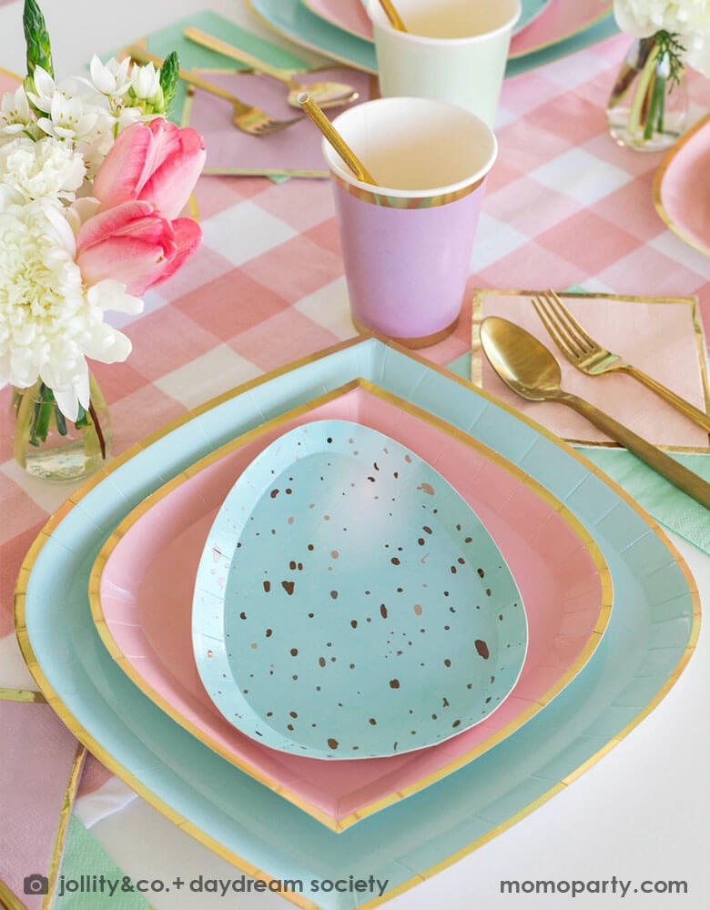 A spring inspired Easter party table placeset featuring Momo Party's pastel themed tableware including pastel mint & pink plates and robin egg shaped plates, lilac party cups, pink gingham table runner and gold utensils. With a spring floral bouquet, this makes a great tablescape for an Easter brunch table or a spring family and friends gathering.