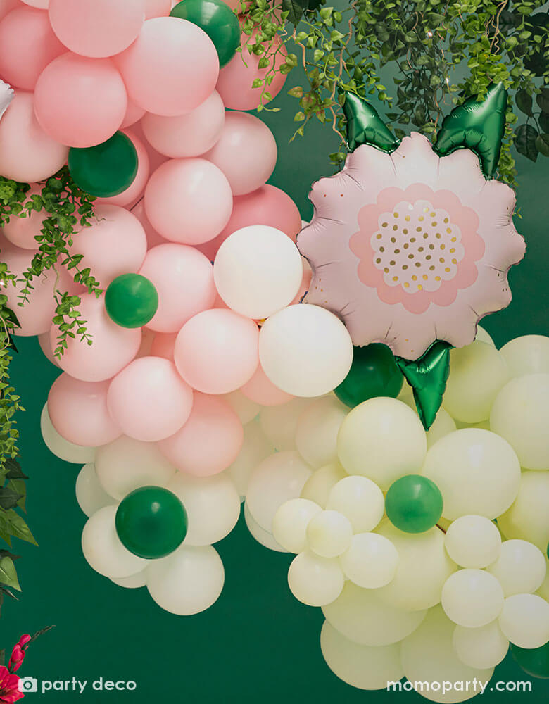 A spring inspired balloon garland in pastel yellow and pink colors peppered with some small emerald green as the green foliage adorned with Momo Party's 23" x 19" pink flower foil balloon, makes this a great balloon decoration for a garden party or spring inspired celebration.