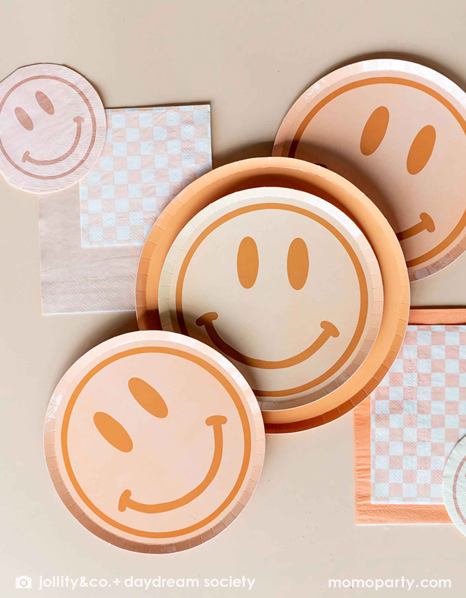Momo Party's Love and Peach collection by Jollity & Co. featuring 8" smily face dessert plate on a peach, 10" dinner plates, pairing with peach and white checkered small napkins and peach large napkins.