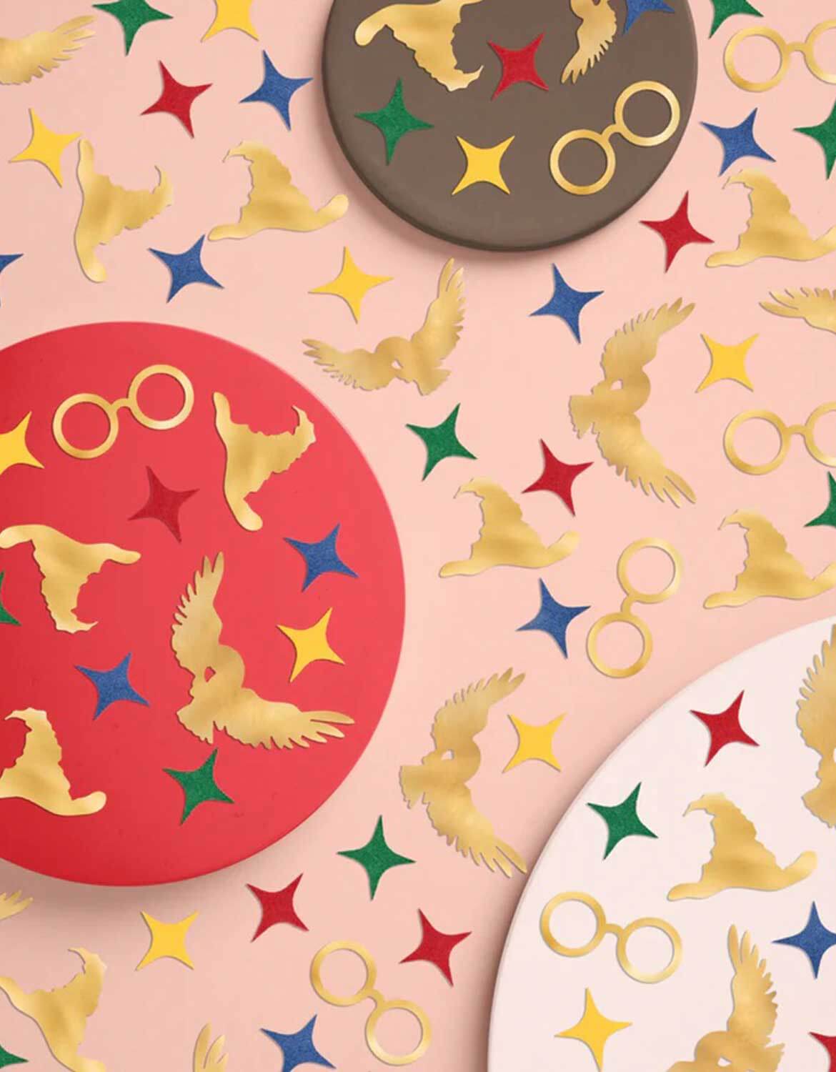Momo Party's Wizard Party Foil Confetti featuring Harry Potter themed designs including starburst in red, green, yellow and red, glasses, sorting hats and owls, on a beige background with a brown, red and white circles.