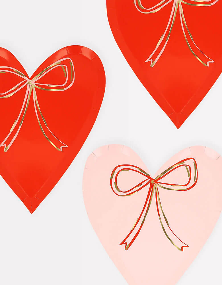 Momo Party's 7.5" x 8.5" Heart With Bow Plates in red and pink by Meri Meri. With shiny gold foil details, these plates are perfect for a sweet Valentine's Day celebration.