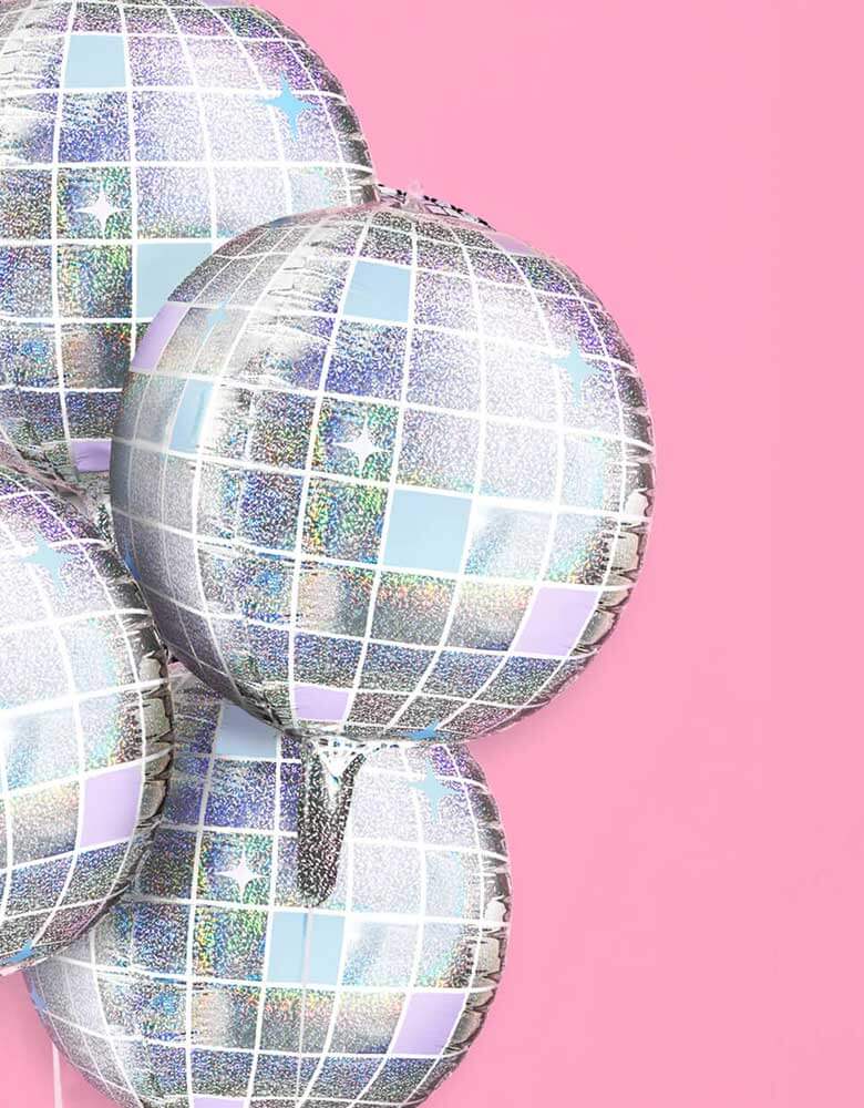 A close up shot of Momo Party's 22" Iridescent Shimmer Disco Ball Foil Balloons by Xo, Fetti. Make the whole place shimmer with these bejeweled disco ball shaped balloons. Perfect for your photo backdrop - this balloon set polishes up real nice. Each set comes with 4 disco ball 22" foil balloons Iridescent, mirrored printed finish balloons include a self-sealing valve, preventing the gas from escaping after it's inflated. The balloon can be inflated with helium to float or with a balloon air inflator.