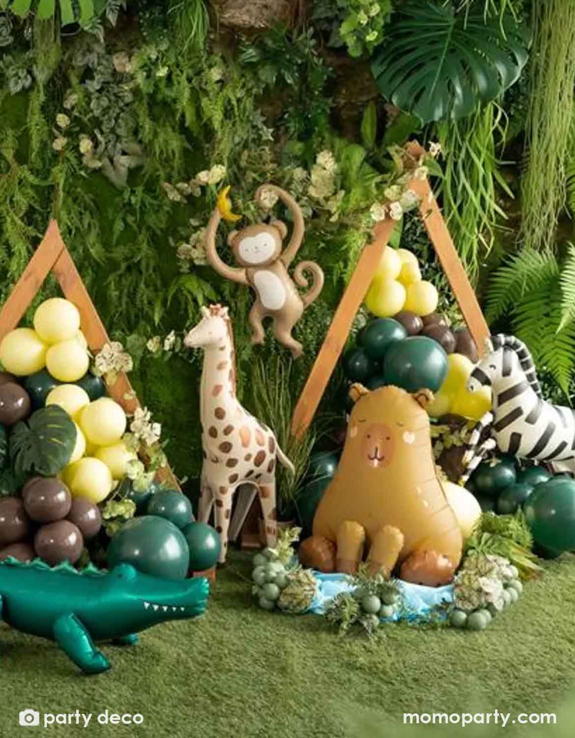 A collection of jungle/safari animal themed foil balloons from Momo Party featuring a zebra, monkey, lion, giraffe, elephant, capybara and crocodile against a jungle decorative backdrop along with some green latex balloon garland, making this a perfect set up for kid's jungle/safari themed birthday party, be it a "Wild One" first birthday party, a "Two Wild" second birthday party or a any adventure themed celebrations.