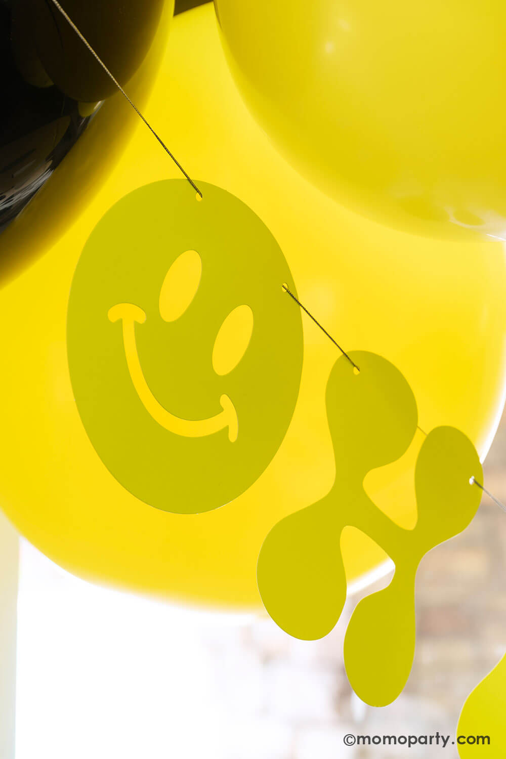 Close up of Momo Party's retro neon happy birthday banner in bright yellow hung below some birthday party balloons. This banner is perfect for for boy's "One Happy Dude" themed first birthday, a "Two Cool" themed second birthday party or "Ten Rad Years" 10th birthday party.