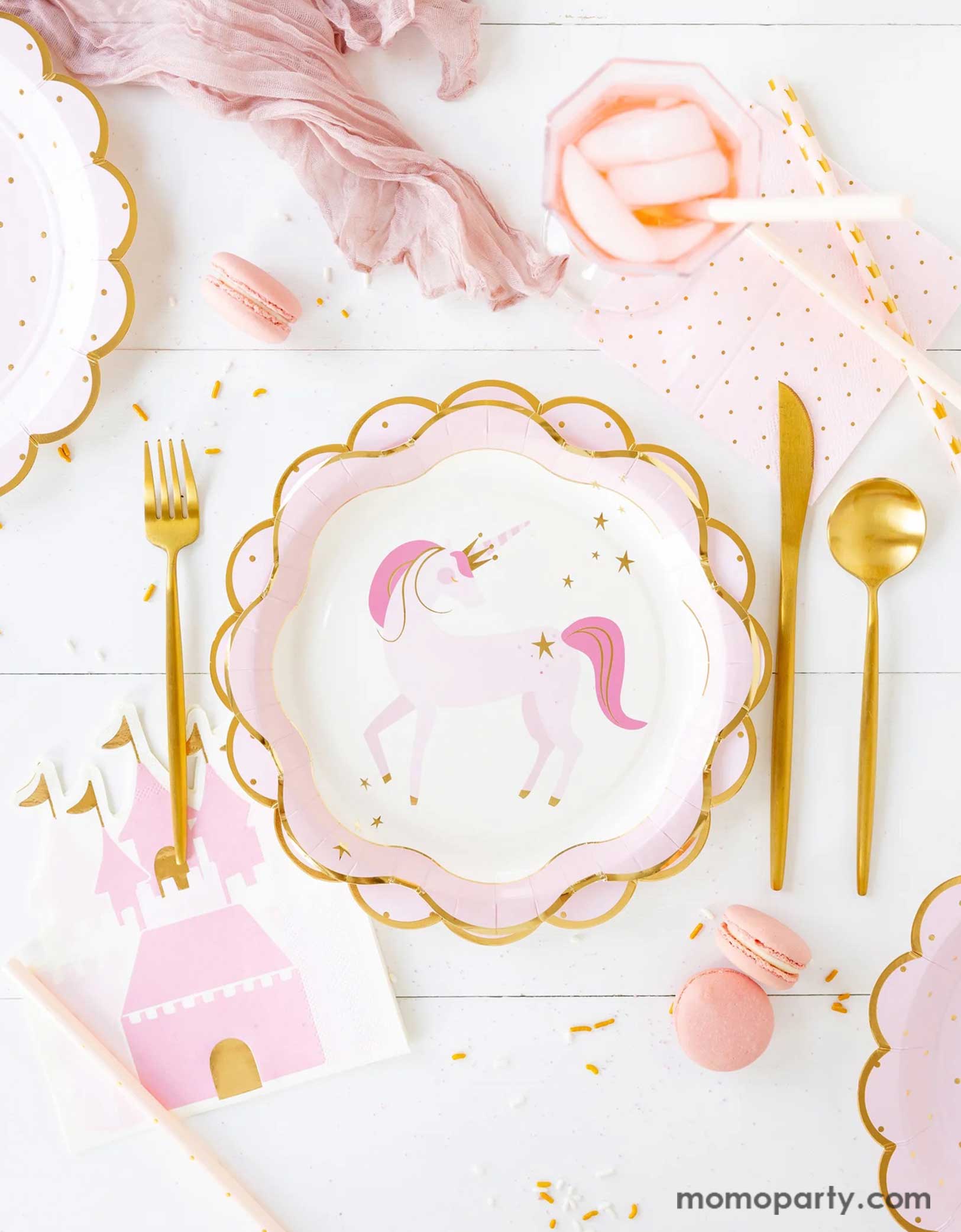 A princess and unicorn themed party tablescape featuring Momo Party's pink party tableware including unicorn plates, princess castle shaped guest napkins, pink polka dot napkins and matching scalloped edged paper plates. Along with pink macarons and gold foil cutlery set, this table is ready for your little royal and her guests in a playful birthday bash!