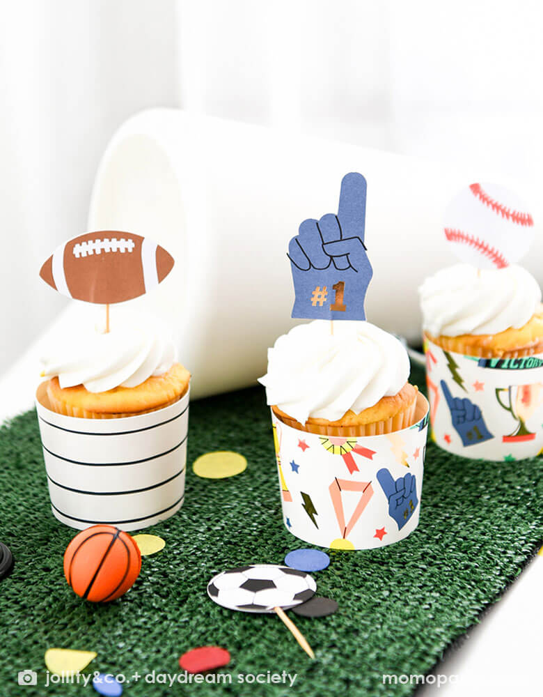 A sport themed party table decorated with faux grass table runner on which are some cupcakes decorated with Momo Party's good sport cupcake decoration kit by Daydream Society. With sport cupcake topper designs like football, baseball, soccer and #1 finger, it makes a perfect addition to any sport themed celebration, be it a kid's sport birthday bash or game viewing party.