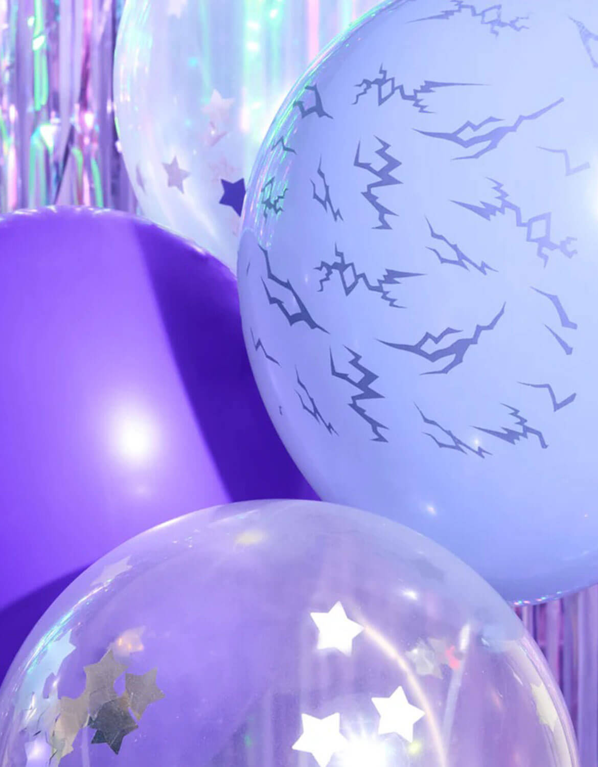 A close-up shot of Momo Party's Kpop Party Latex Balloon Mix in purple, lilac and clear with silver stars against purple tinsel party backdrop in the background.