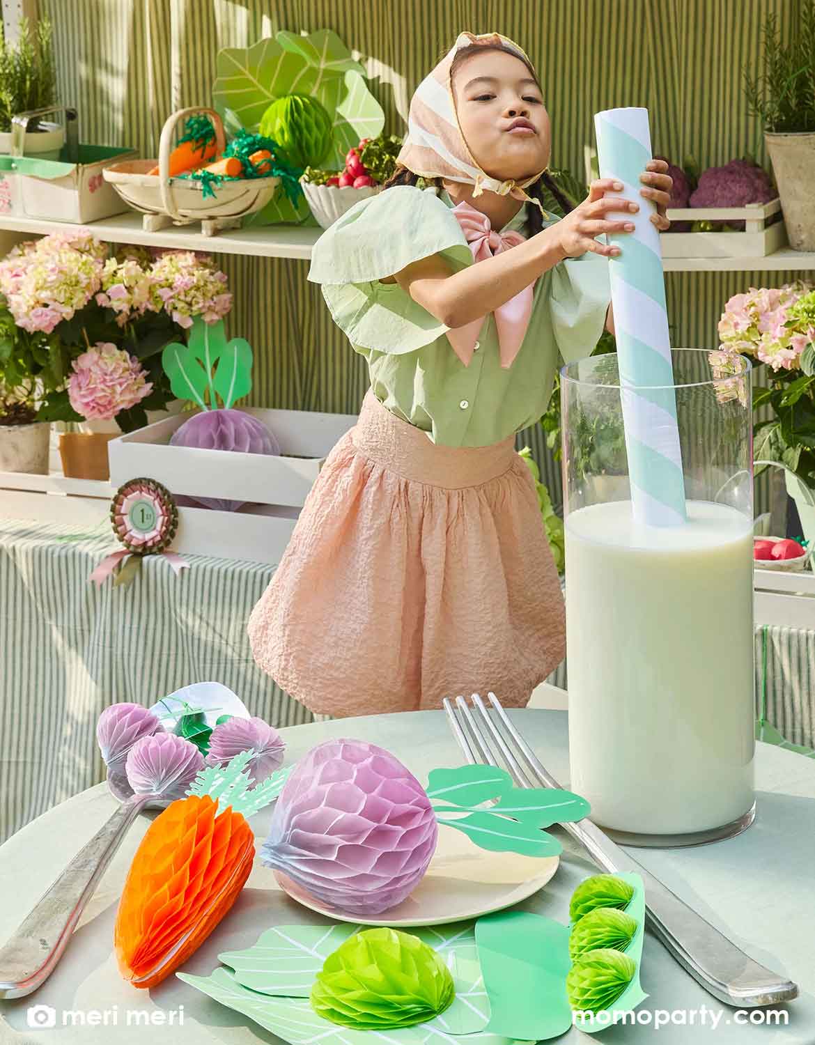 Child at a party table with decorative items and a glass of milk.