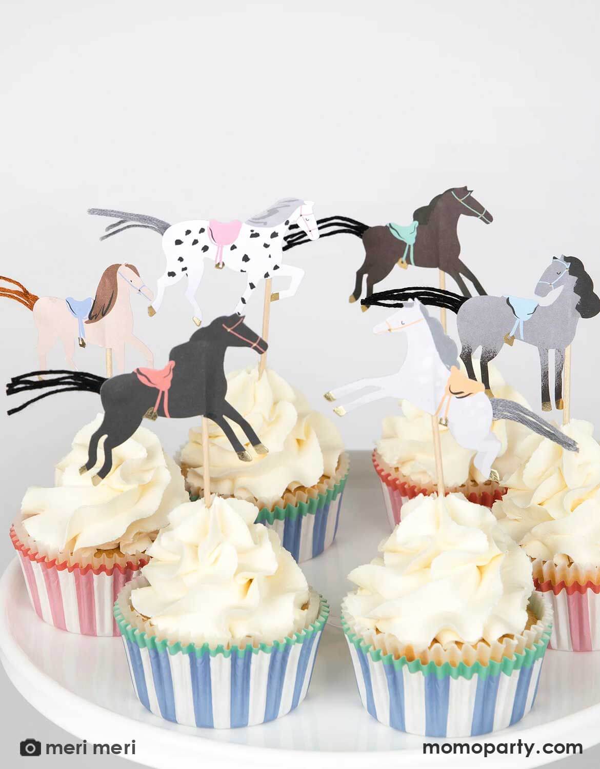 Cupcakes topped with Momo Party's horse-themed toppers and striped wrappers by Meri Meri on a white background.
