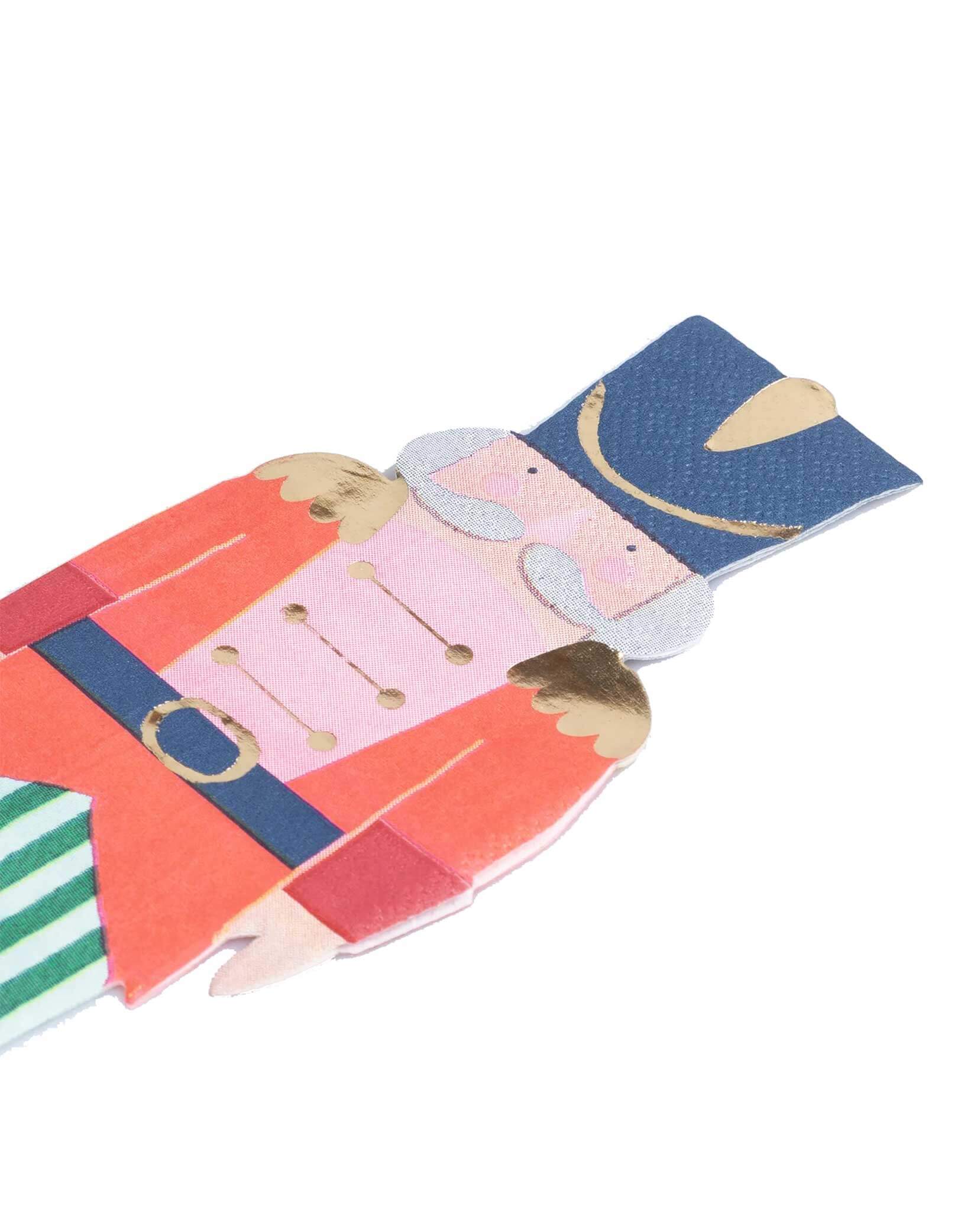 A close-up shot of Momo Party's 3" x 7.625" Nutcracker soldier shaped napkin with gold foil accents by Meri Meri on a white background.