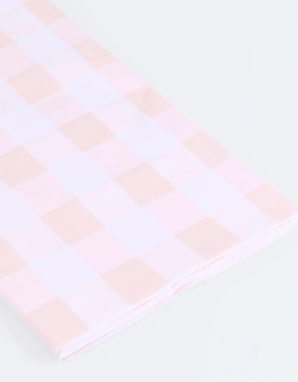 A close up of Momo Party's paper tablecloth with pink and white checkered design by Meri Meri on a white background.