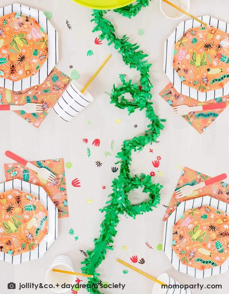 A kid's bug theme birthday party table filled with Momo Party's backyard bug themed party supplies and tableware including plates, napkins and confetti. With neon tone bugs in modern illustrations. Along with black striped plates and party cups, these bug themed partyware if perfect for your child's crawling bug inspired party!