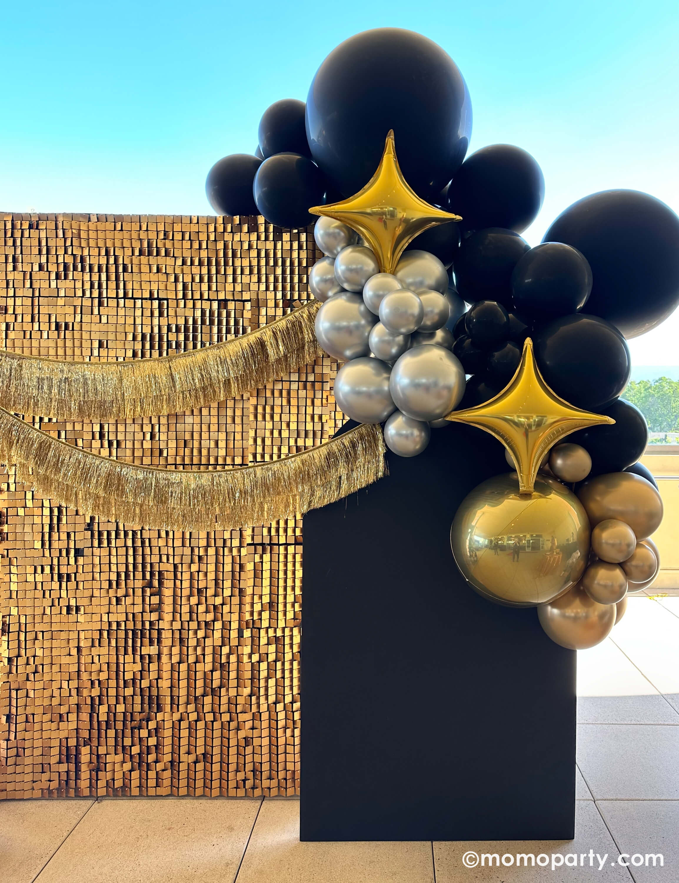 Presented by Momo Party, this luxe black, gold, and silver balloon garland with Large Gold Starpoint Foil Mylar Balloon, and a shimmering sequin backdrop and gold fringe accents is perfect for Hollywood parties, New Year’s Eve, auctions, and milestone celebrations. A bold, photo-worthy statement piece! 🎉✨