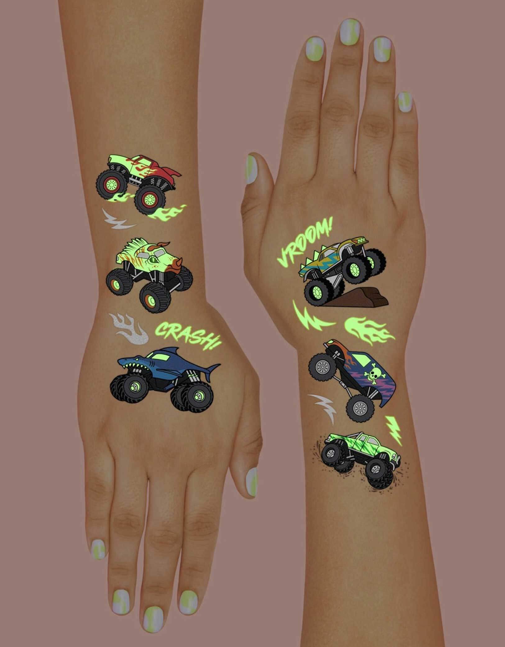 Two hands decorated with Momo Party's 8.25" x 6" Monster Truck Glow in the Dark Kids Temporary Tattoos by xo, fetti. Comes in a set of 50 tattoos, these awesome glow-in-the-dark Monster Truck temporary tattoos are guaranteed to be a wheel good time at your kid's Monster Truck birthday party! 50 designs means nobody gets left behind - invite all of your bffs to crash this party because these tats are sure to be fire!
