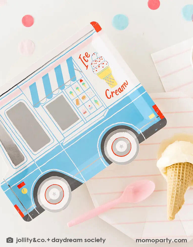 A festive party table featuring Momo Party's 10.5″ x 8″ Ice Cream Truck Plate by Daydream Society. Next to the ice cream truck plate there were a pink striped plate and napkin holding a scoop of ice cream in a waffle cone.
