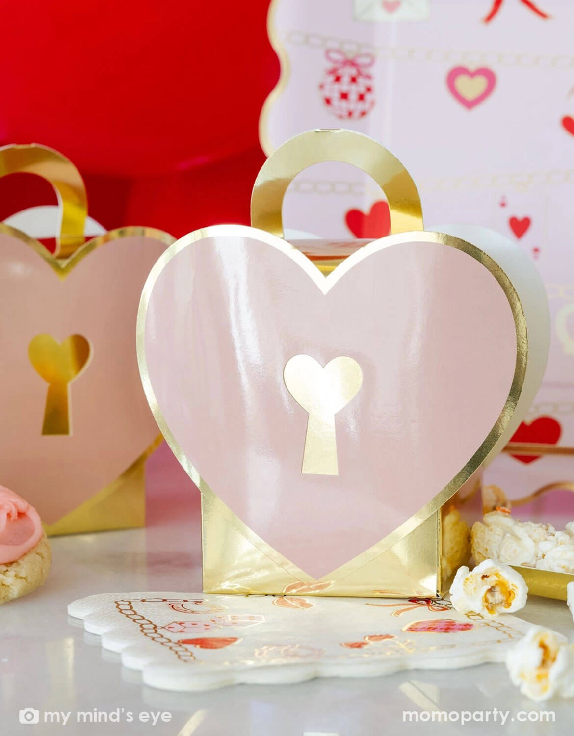 Heart-shaped pink and gold cookie box with a lock design on a decorative table.