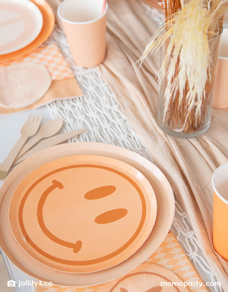 A BOHO love and peace themed party table, decorated with Jollity & Co Peace & Love Smile Dessert Plates overlay with Shade plates with checked it napkins. these plates will bring good vibes to any girl's birthday.