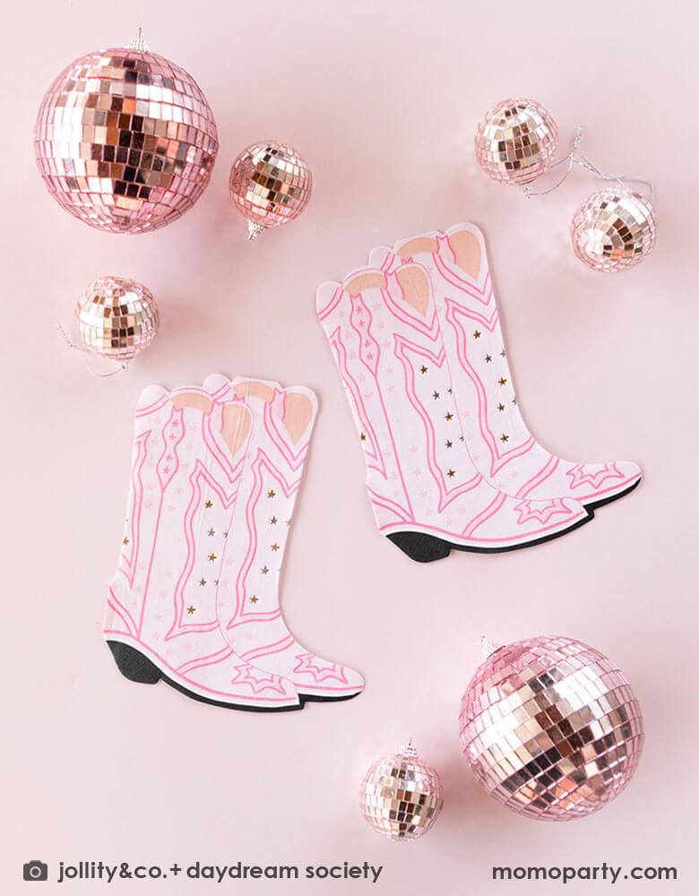 Momo Party's 7.25 x 6.25 inches Cowgirl Boots Shaped Large Napkins by Daydream Society on a light pink table. Around the napkins are some festive pink disco ball decorations, making this a great inspo for a cowgirl disco "Let's Go Girls" themed celebration, be it a little girl's First Rodeo first birthday party or a disco cowgirl themed bachelorette party.