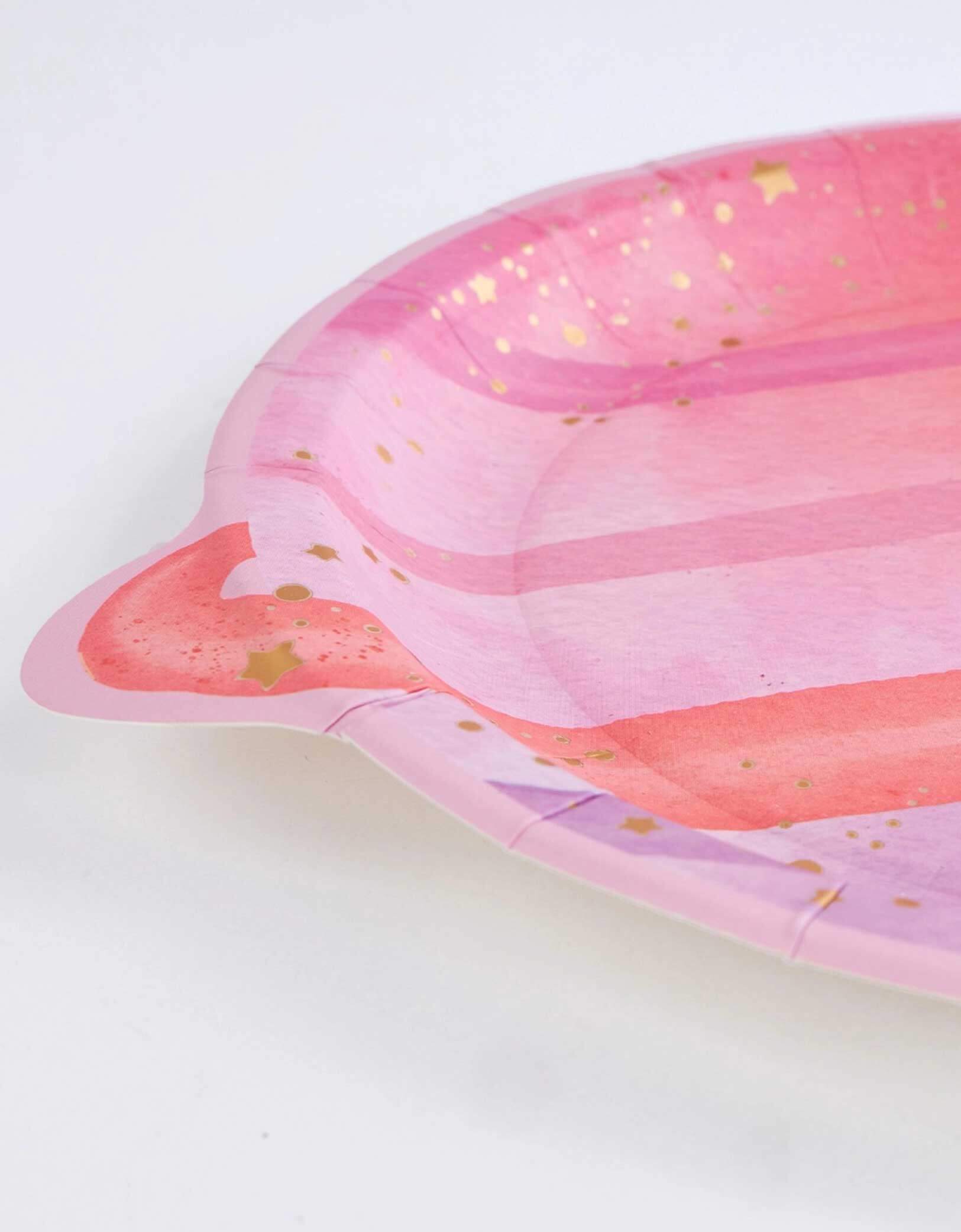 A closeup shot of Momo Party's 8" Pink Planet shaped Plate with gold speckles on a white background.