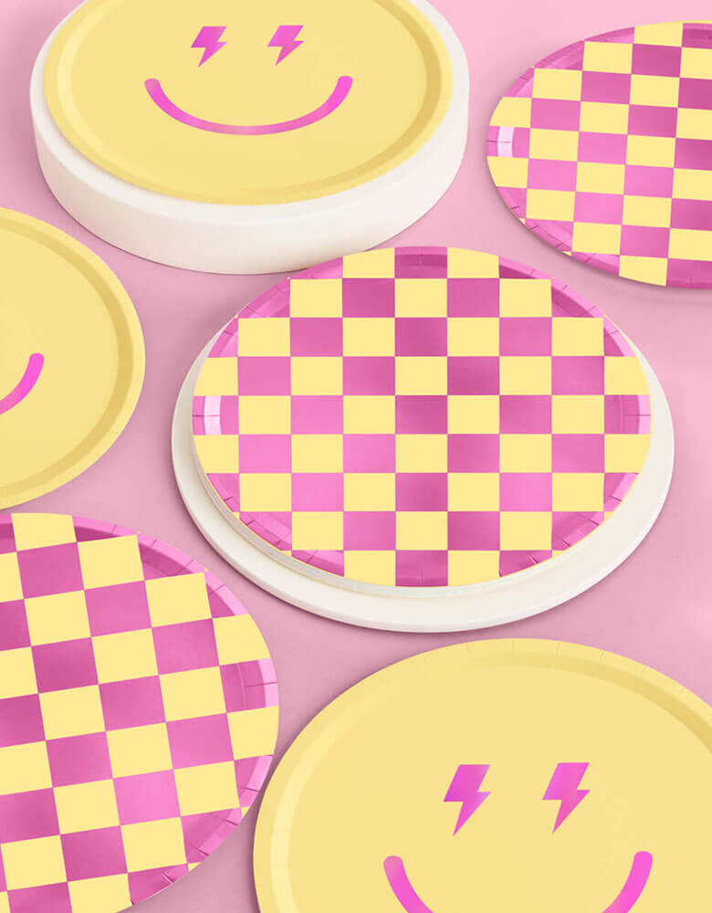Momo Party's 9" Preppy Party Plates by Xo, fetti. Comes as 24 paper plates a set in two different colors/designs including yellow and pink checkers and a smiely face with lighting bolt eyes in pink, these groovy paper plates are perfect for a retro themed happy celebration.
