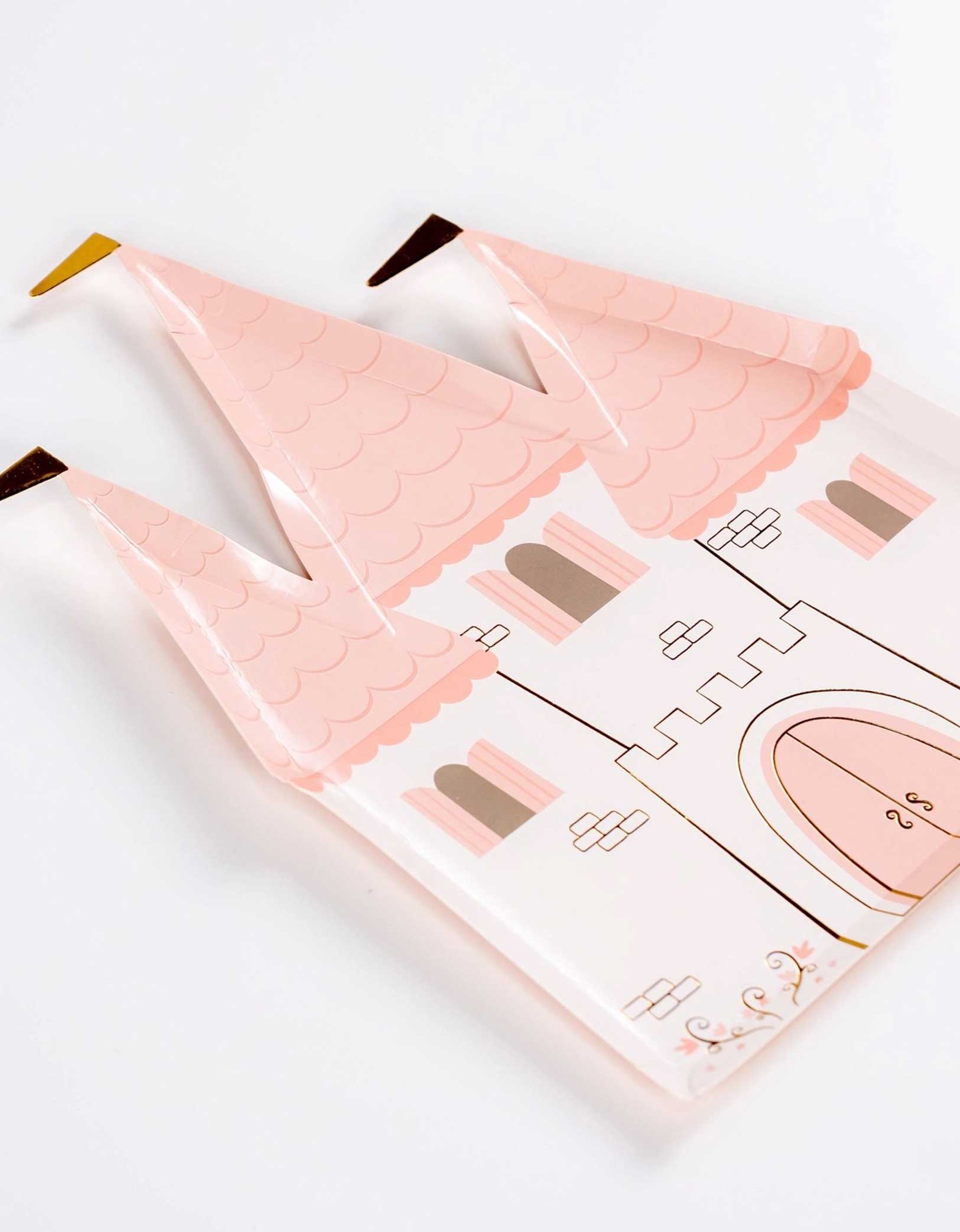 A closeup look at Momo Party's 9.5" castle-shaped princess party plate with pink rooftops and gold foil accents on a white background.