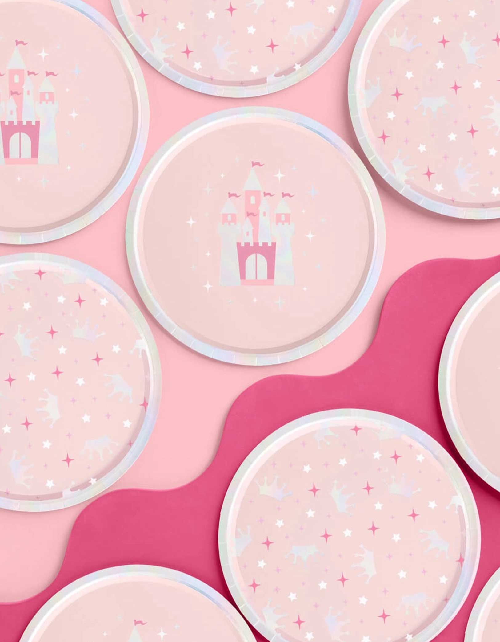 Momo Party's 9" princess iridescent round party plates in two designs each featuring a pink castle design and crowns and star point patterns on a pink background.