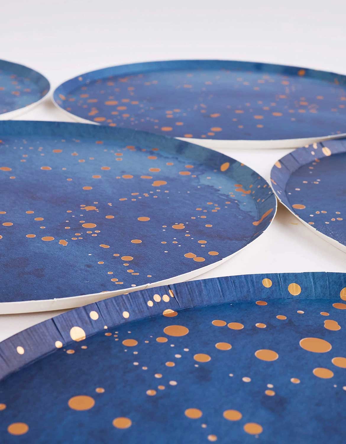 A close up shot of Momo Party's 10" Blue Gold Dust Large Paper Plates with gold speckles on a white background.