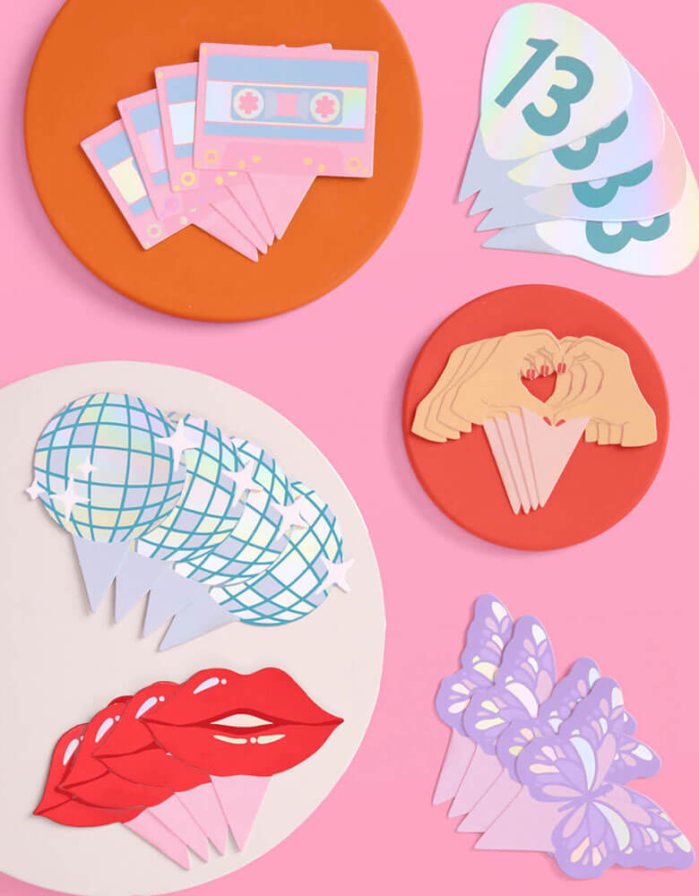 Momo Party's Era's Party Cupcake Toppers by Xo, Fetti. Comes in a set of 24, these Taylor Swift-themed dessert/cupcake toppers are with iconic designs including butterflies, red lips, disco balls, cassettes, guitar picks and heart hand symbols. They're perfect for to celebrate your Swiftie girl's special birthday.