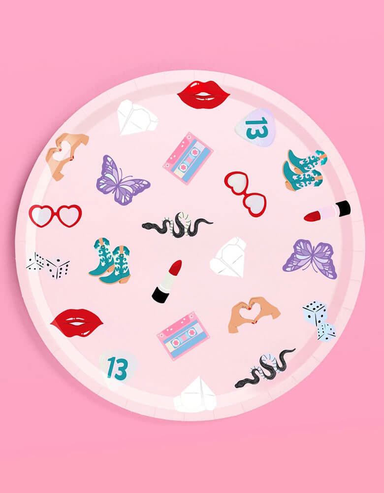Momo Party's 9" x 9" Taylor Swift Era's Party Paper Plate by Xo, Fetti. This paper plate features Taylor Swift inspired motif featuring red lipstick, red lips, butterflies, cowgirl boots, snakes, cassette tapes, guitar picks, heart hand symbols, and heart shaped sunglasses. It's perfect for the party table celebrating your Swiftie girl's special day.