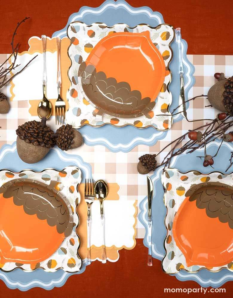 A beautiful fall tablescape featuring Momo Party's fall themed tableware including the acorn shaped paper plates, orange napkins and brown gingham table runner, with acorn bouquet and decorations, this makes a great inspo for a fall party or Thanksgiving gathering table decoration idea.