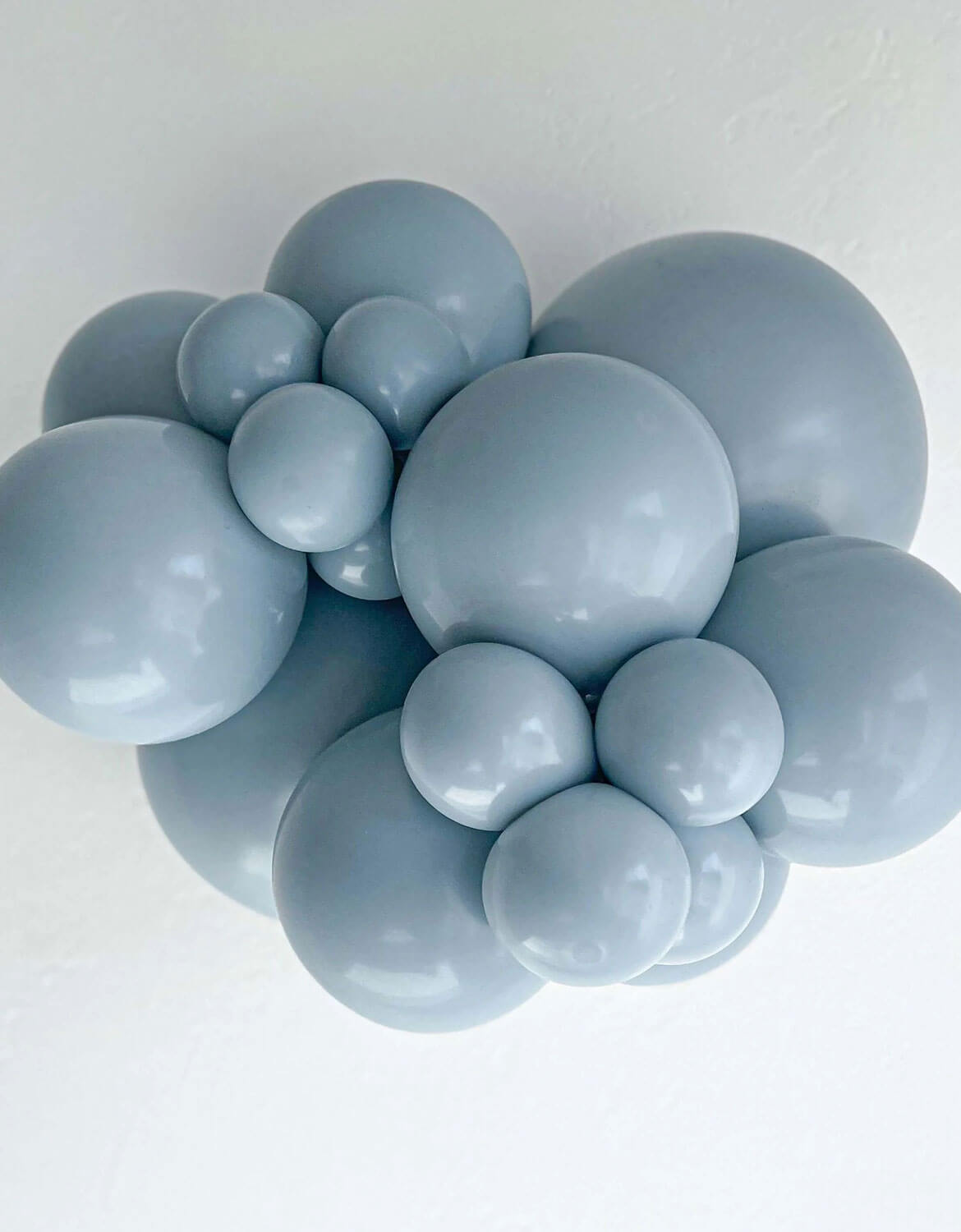 A cluster of Tuftex fog latex balloons in different sizes in a dusty light blue-gray color, arranged against a plain white background.