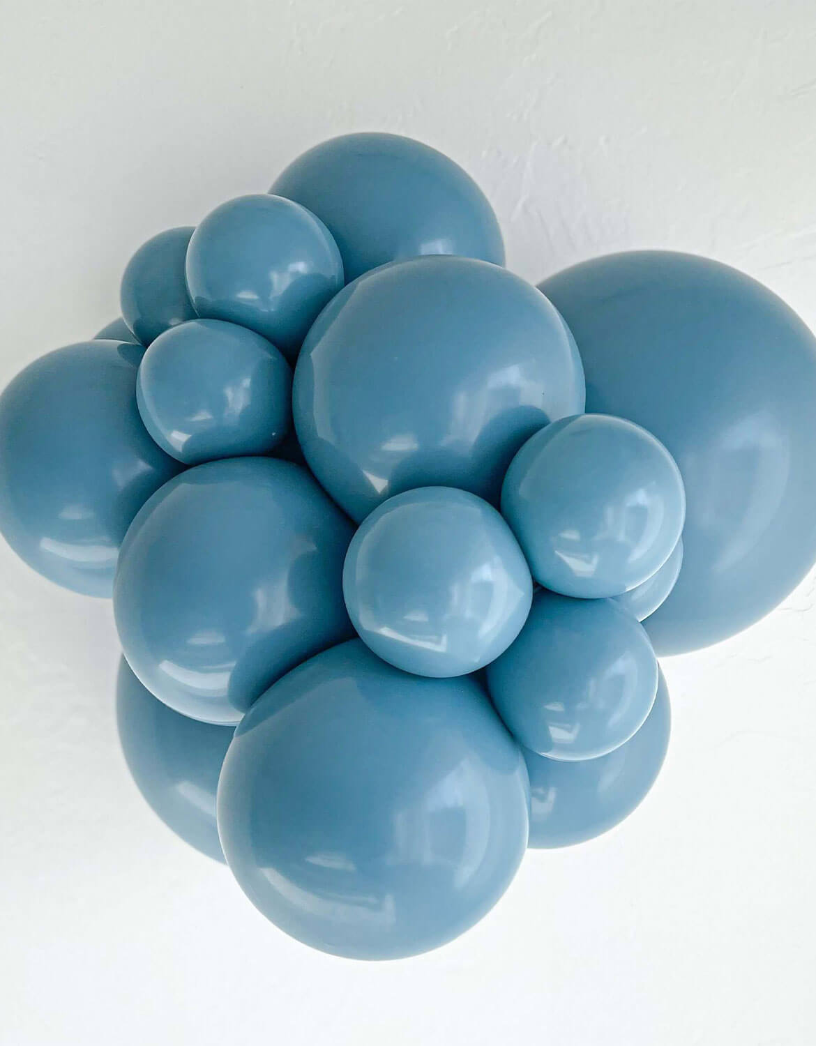 A cluster of Tuftex matte dusty blue balloons arranged in a decorative cluster shape against a plain white background.