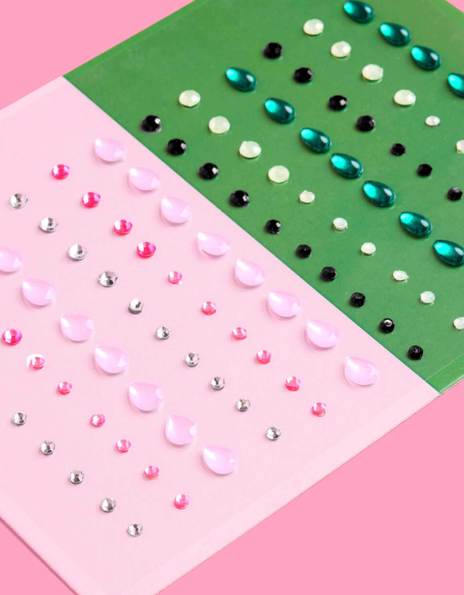 Momo Party's Wicked Pink Green Face Gem Set featuring two gem sets in pink and green packaging on a pink background. Comes in 112 pieces, these adhesive gems stick easily and stay put, ensuring your look shines brightly throughout the entire night.