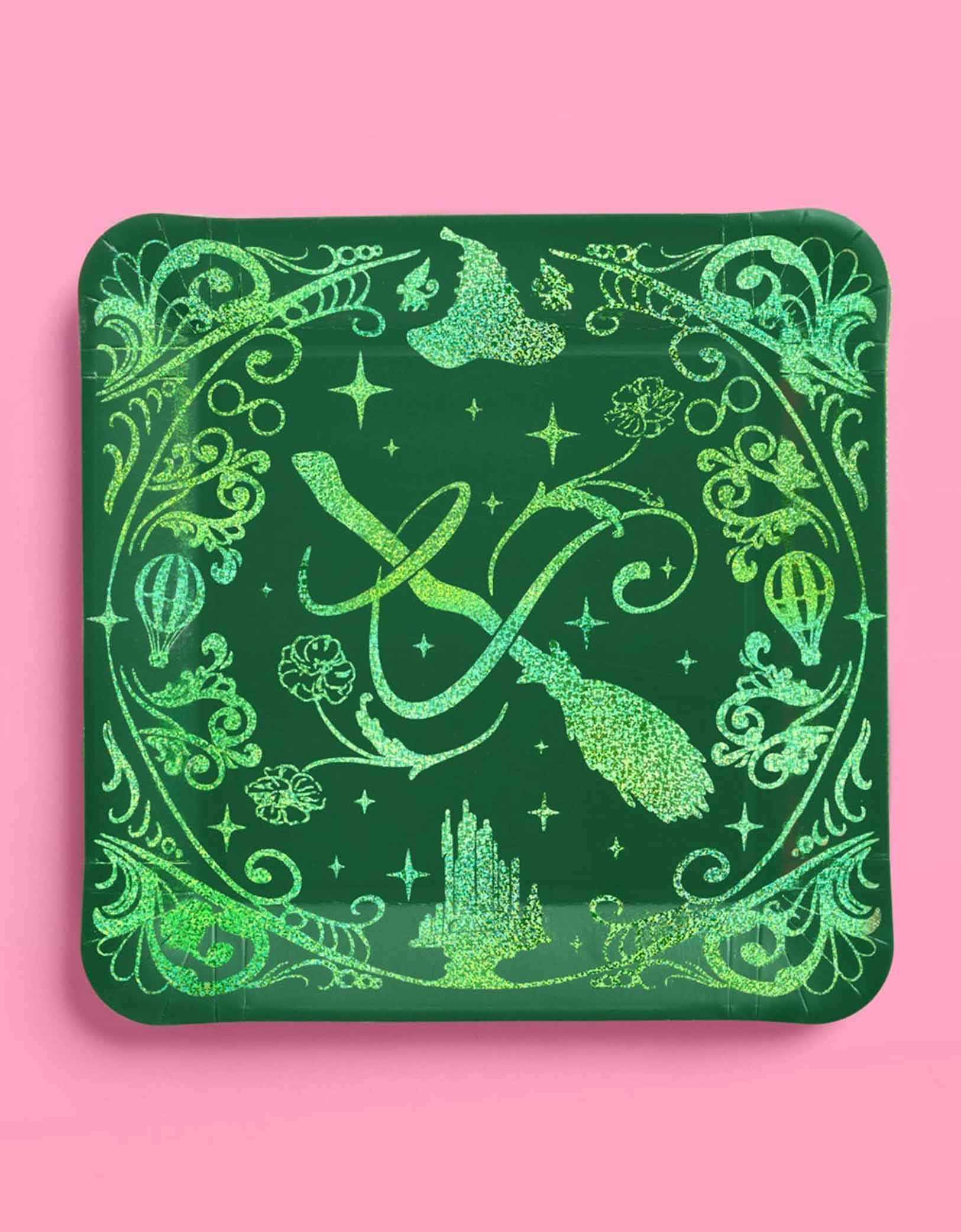 Momo Party's 10.5" Wicked party dinner plates in green with intricate wizard and Elphaba inspired designs on a pink background.
