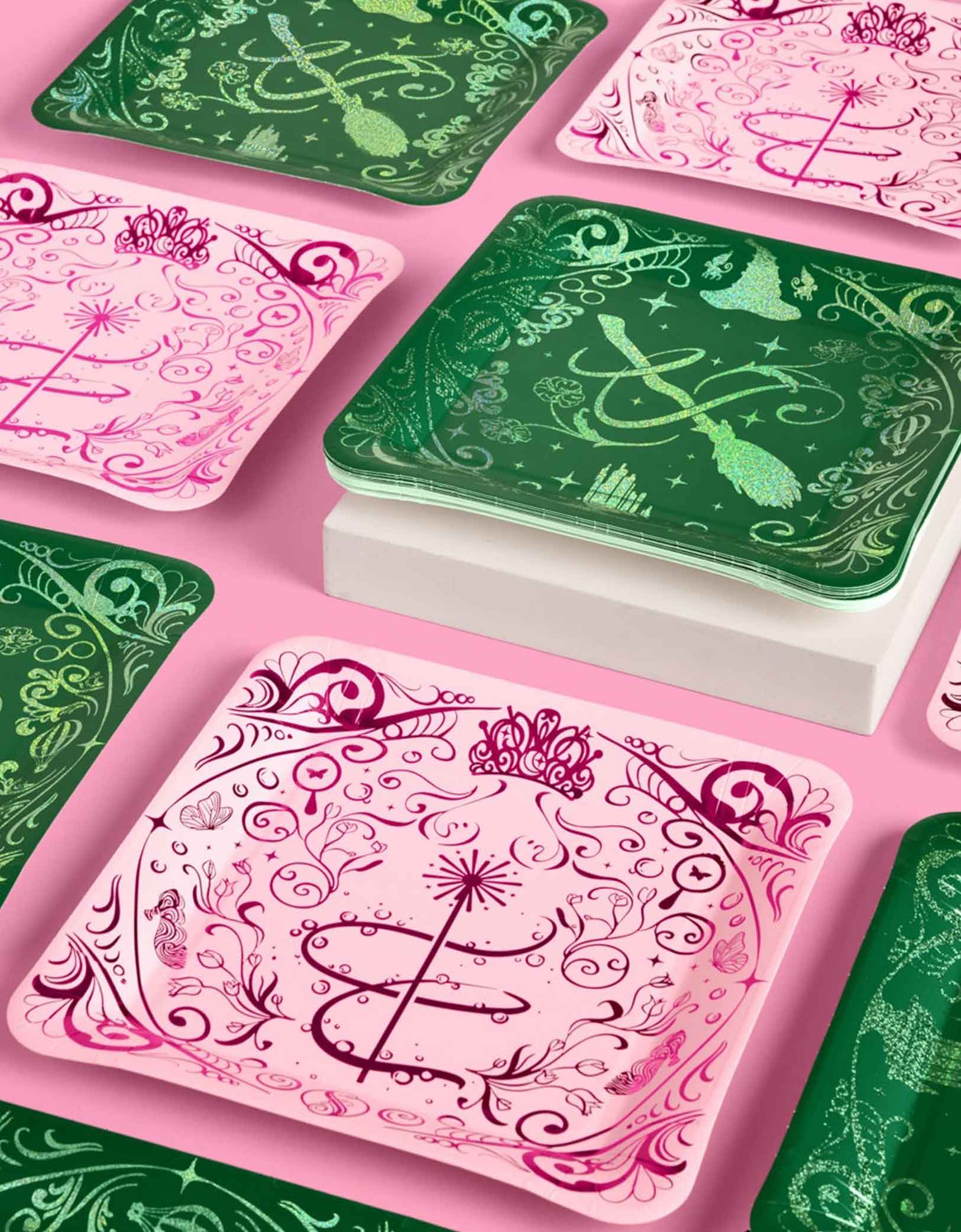 Momo Party's 10.5" Wicked Party dinner plates with intricate wizard Elphaba and Glinda inspired designs in pink and green designs on a pink background.