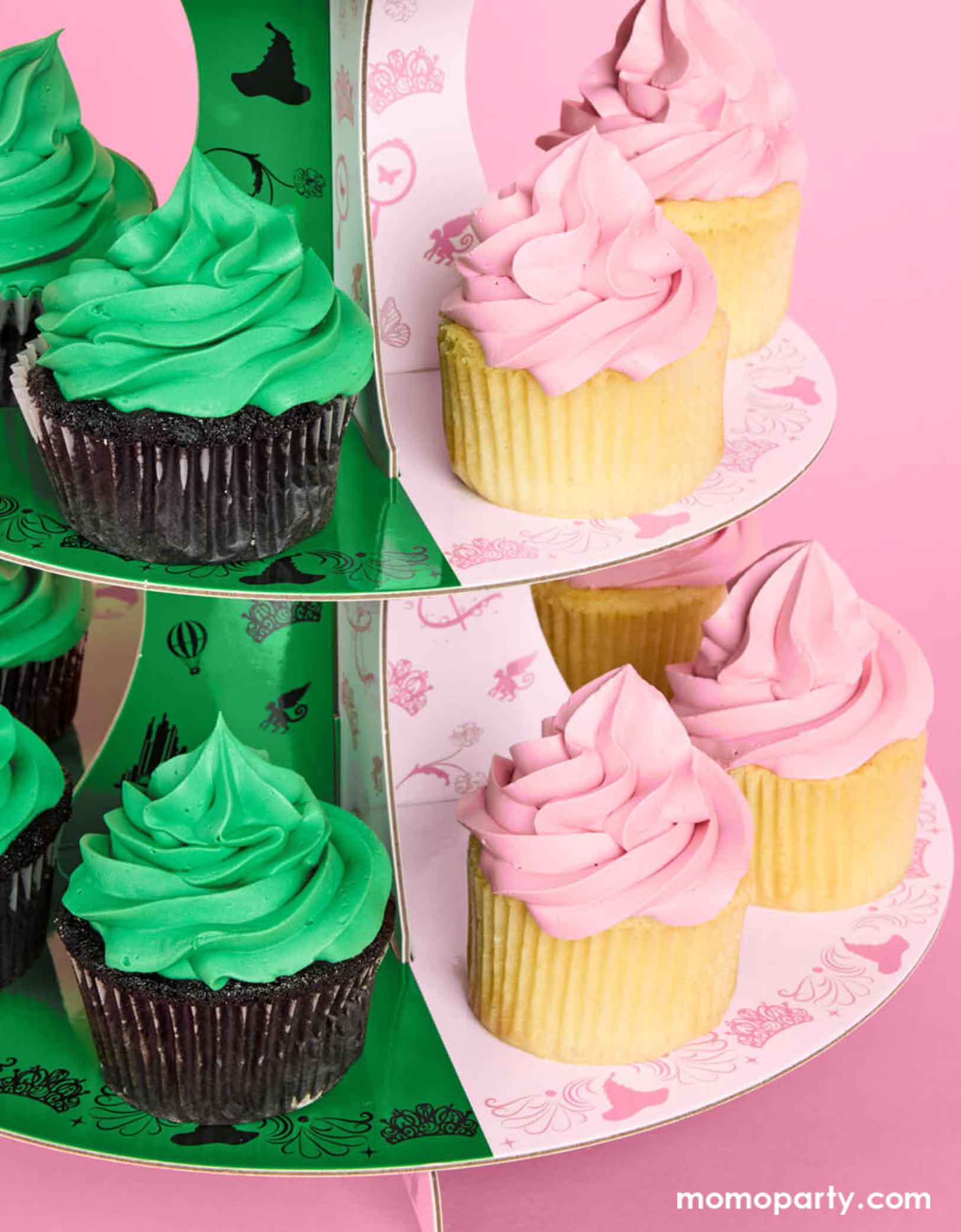 Cupcakes with green and pink frosting on Momo Party's green and pink cake stand with Wicked's Emerald City design at the top on a pink background. Inspired by the enchanting world of the Wicked Witch, this green and pink centerpiece adds a whimsical flair to any celebration. Perfect for showcasing your sweet treats, it transforms your dessert table into a dazzling scene straight from the Emerald City.