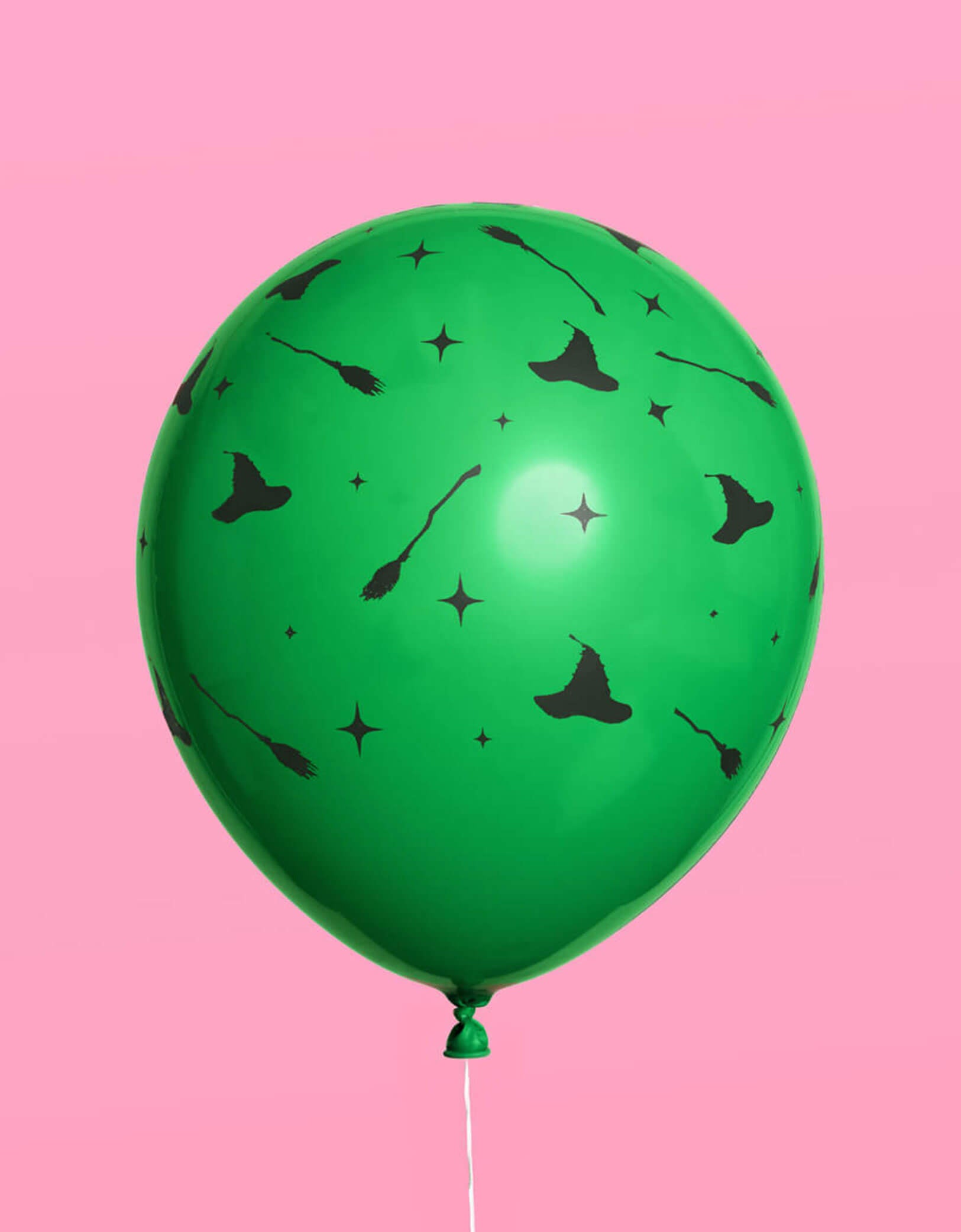 A green Wicked themed latex balloon with witch themed patterns including witch hats, witch brooms, and star points on a pink background.